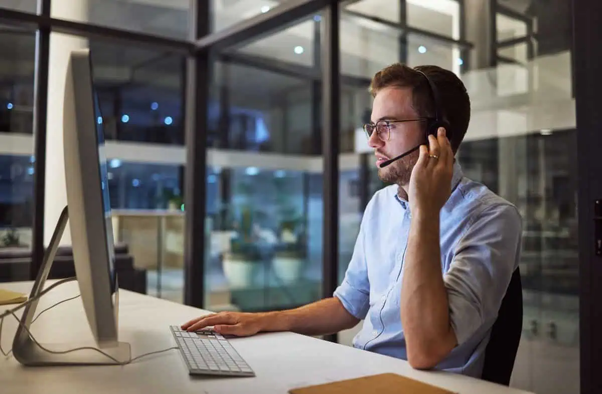 a man wearing a headset and looking at a computer